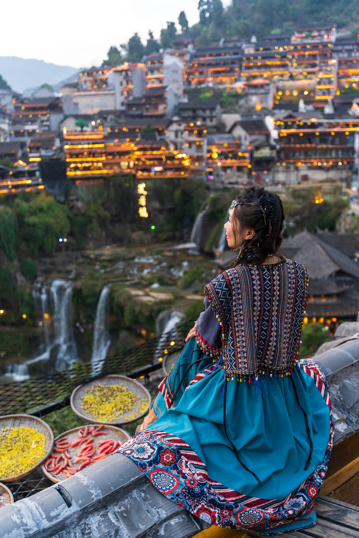 Mujer China sentada admirando la Ciudad de Lijiang